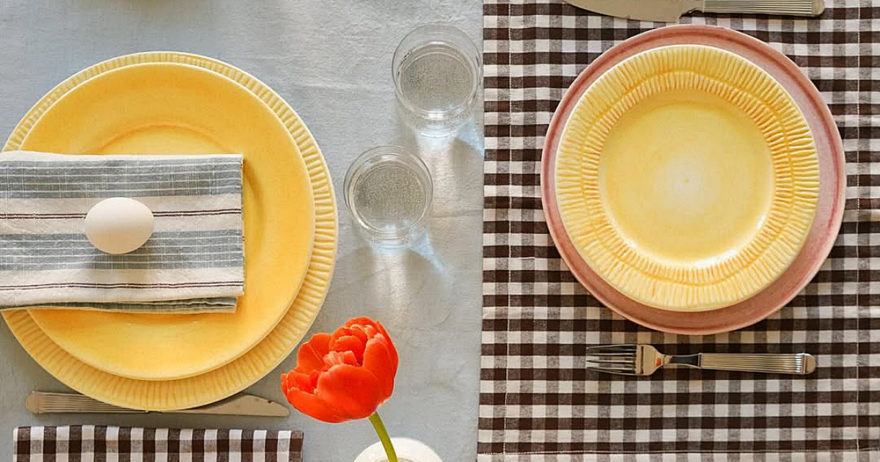 ギンガムチェックのマットにマテュースの黄色やライトピンクのプレート、チューリップ、ミモザ、卵を並べたイースターの食卓風景