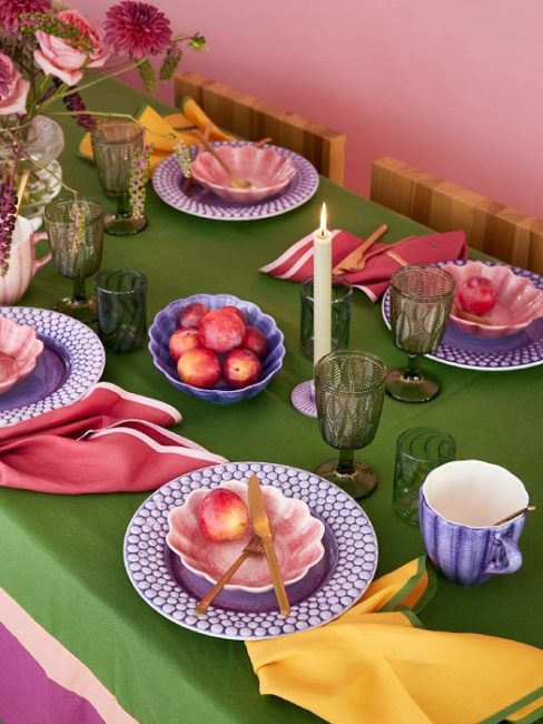緑色のテーブルクロスに、マテュースのパープルのバブルプレートやピンクのオイスターボウルを重ねた華やかなテーブルコーディネート