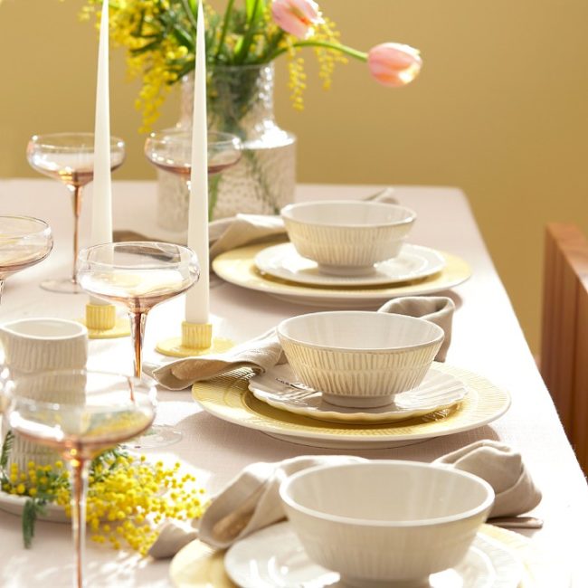ミモザとチューリップが添えられたイエローとサンドカラーの食器でコーディネートされた春の食卓